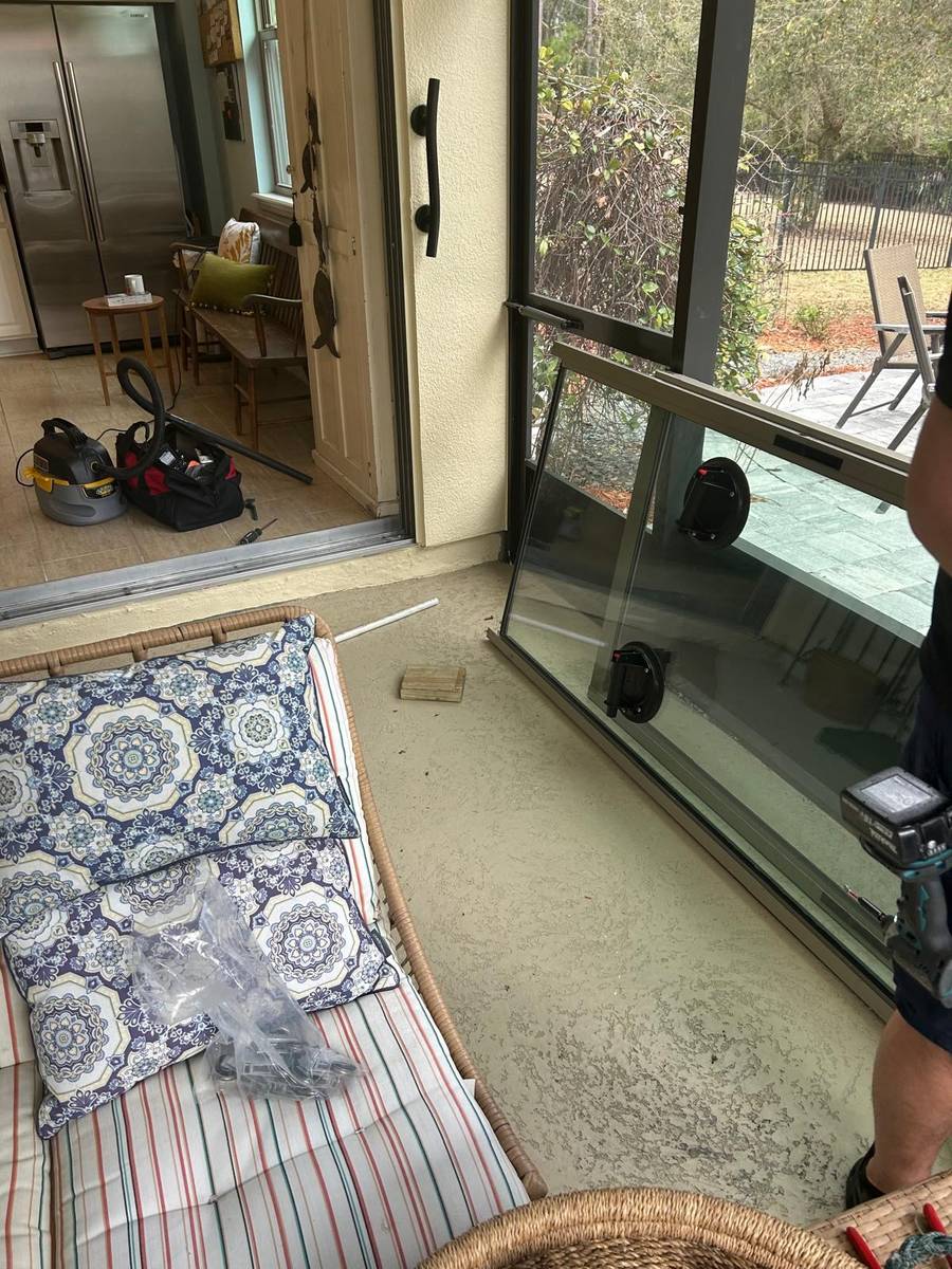 Technician removing a full sliding door glass panel for replacement